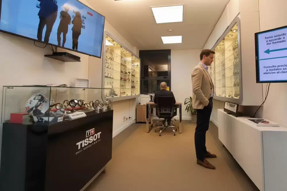 Showroom de Regalos Empresariales en CABA, con vitrinas de relojes Tissot y personal atendiendo a un cliente